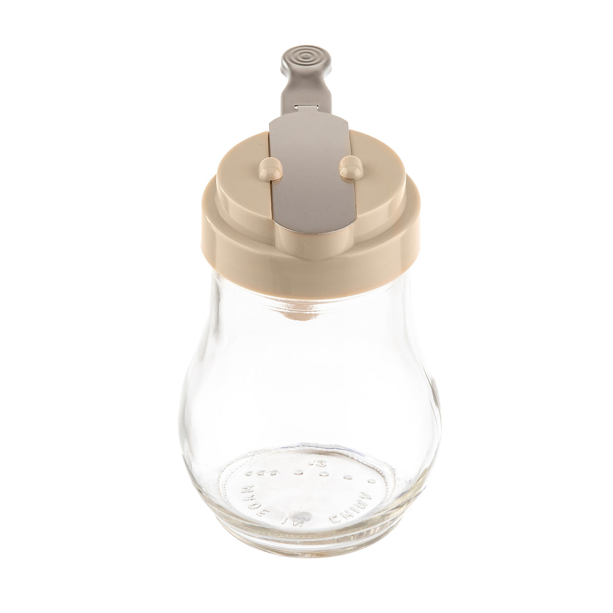 A clear teardrop glass dispenser with a beige plastic lid and gray metal lever mechanism sits on a white background. The jar is empty, clean, dishwasher safe, and features no visible labels or markings on its sides.