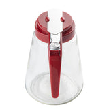 A clear teardrop glass syrup dispenser with a wide base, red plastic lid, and matching handle featuring a silver metal lever mechanism for pouring. This dispenser is viewed from above on a white background and is dishwasher safe.