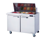 A Blue Air stainless steel sandwich prep table with wheels, two doors, and a mega top filled with containers of assorted vegetables and ingredients—like sliced onions, peppers, and tomatoes—ready for food preparation.