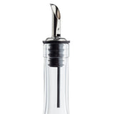 A close-up view of a transparent bottle with a stainless steel liquor pourer. The spout has a narrow, curved opening and is fitted with a black rubber seal. The bottle’s neck and clear liquid are visible against a white background.