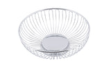 A round, chrome plated TableCraft chalet basket with evenly spaced vertical metal bars radiating from a solid circular base and flaring outward, creating a simple and modern look. The open design pops against the plain white background.