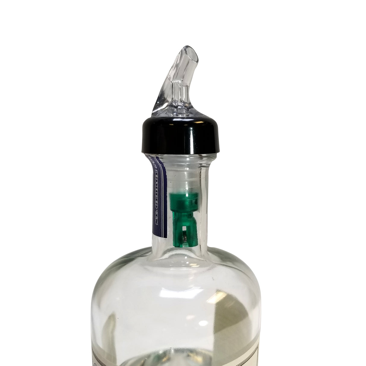 A clear glass bottle with a TableCraft black plastic Proper Pour spout and transparent angled nozzle. Inside the bottleneck is a green 3/4 oz pourer. The image is set against a plain white background, focusing on the bottle’s top portion.