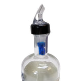 A clear liquor bottle with a black TableCraft pour spout inserted into the neck. Inside, a blue security pourer ensures Proper Pour control and prevents tampering or refilling, all displayed against a plain white background.