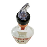 A clear glass bottle with a black neck and a TableCraft 1 oz. pourer features a transparent plastic spout. Mostly empty, the bottle has a partially visible red and white label. The image is taken from an overhead angle against a white background.