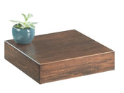 A small green potted plant in a blue ceramic pot sits on the corner of a square, dark brown walnut riser floating shelf against a plain white background.