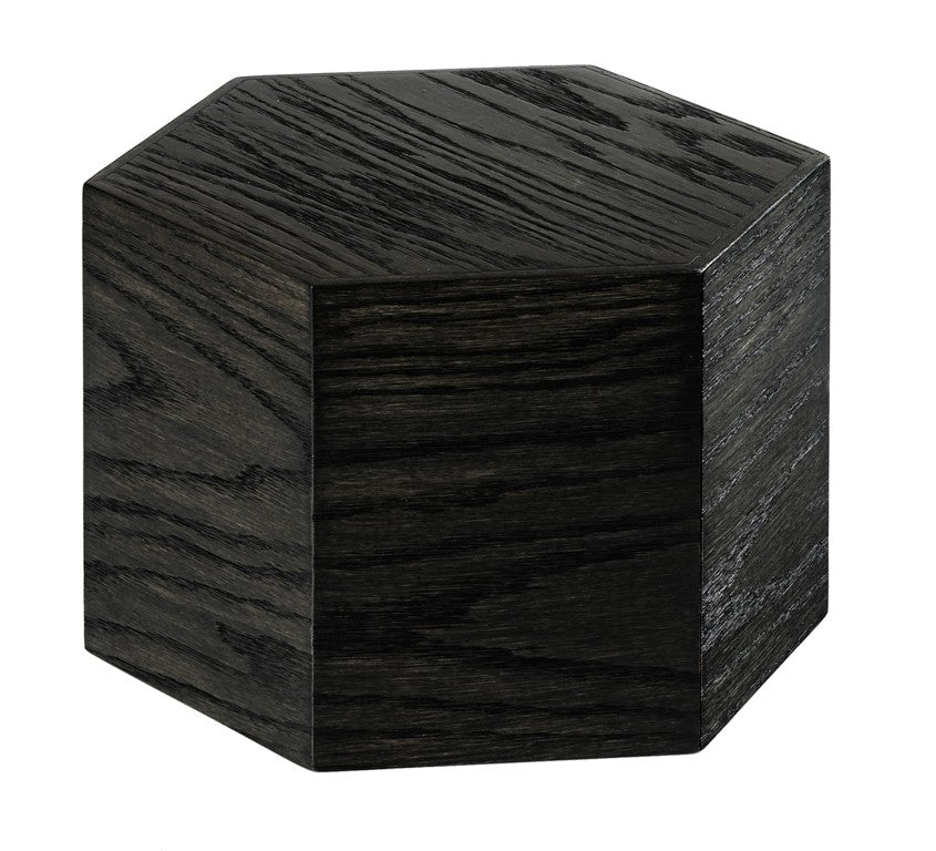 A dark, hexagonal wooden block made from oak wood with visible grain patterns is shown against a white background. The six-sided Cinderwood Riser adds a modern, geometric touch and is crafted from BPA Free materials for safety.