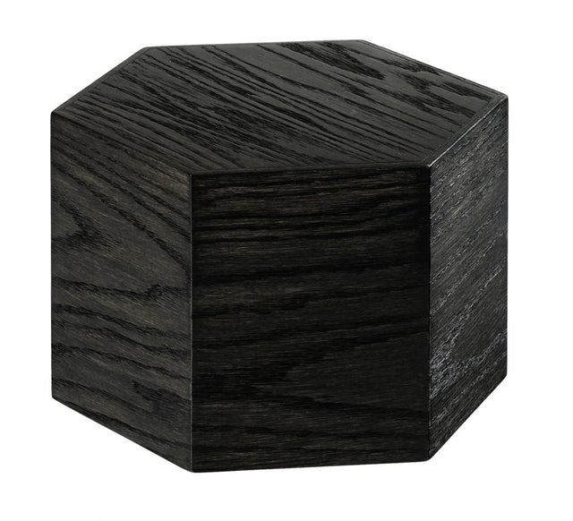 A dark, hexagonal wooden block made from oak wood with visible grain patterns is shown against a white background. The six-sided Cinderwood Riser adds a modern, geometric touch and is crafted from BPA Free materials for safety.