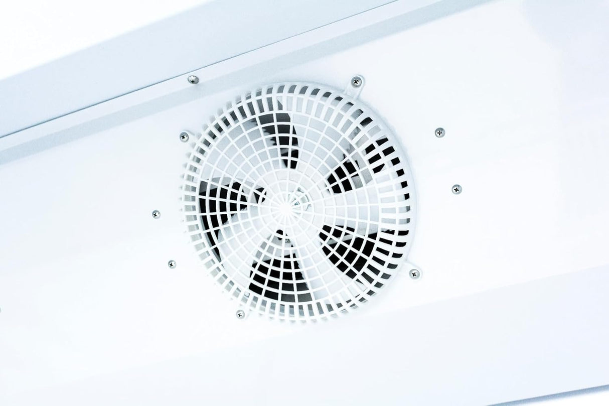 A close-up of a white ceiling fan with a protective white plastic grille, similar to those found above Empura Refrigeration units or Refrigerated Merchandisers, with black blades visible through the grille and small screws securing the housing.