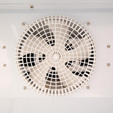 Close-up of a circular ventilation fan with a white protective grid, mounted on a smooth, white surface—similar to those found in Empura Refrigeration or refrigerated merchandiser units. The clean, industrial look highlights the sturdy fan frame and visible blades.