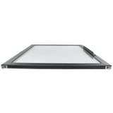 A rectangular glass window from Empura Refrigeration with a slim black frame is shown lying flat, viewed from a low angle at one end. A horizontal handle is visible on the upper right side of this Empura Parts door. The glass surface reflects some light.