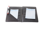 A black leather TableCraft check presenter is open, showing two blue-and-white guest check slips and a red-and-white pen tucked into the left pocket, isolated on a white background.