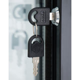 A close-up of a key inserted into the lock of a commercial refrigerator, with a second identical key hanging from the keyring. The keys have black plastic heads with logo engravings; the metallic frame reflects light in the background.