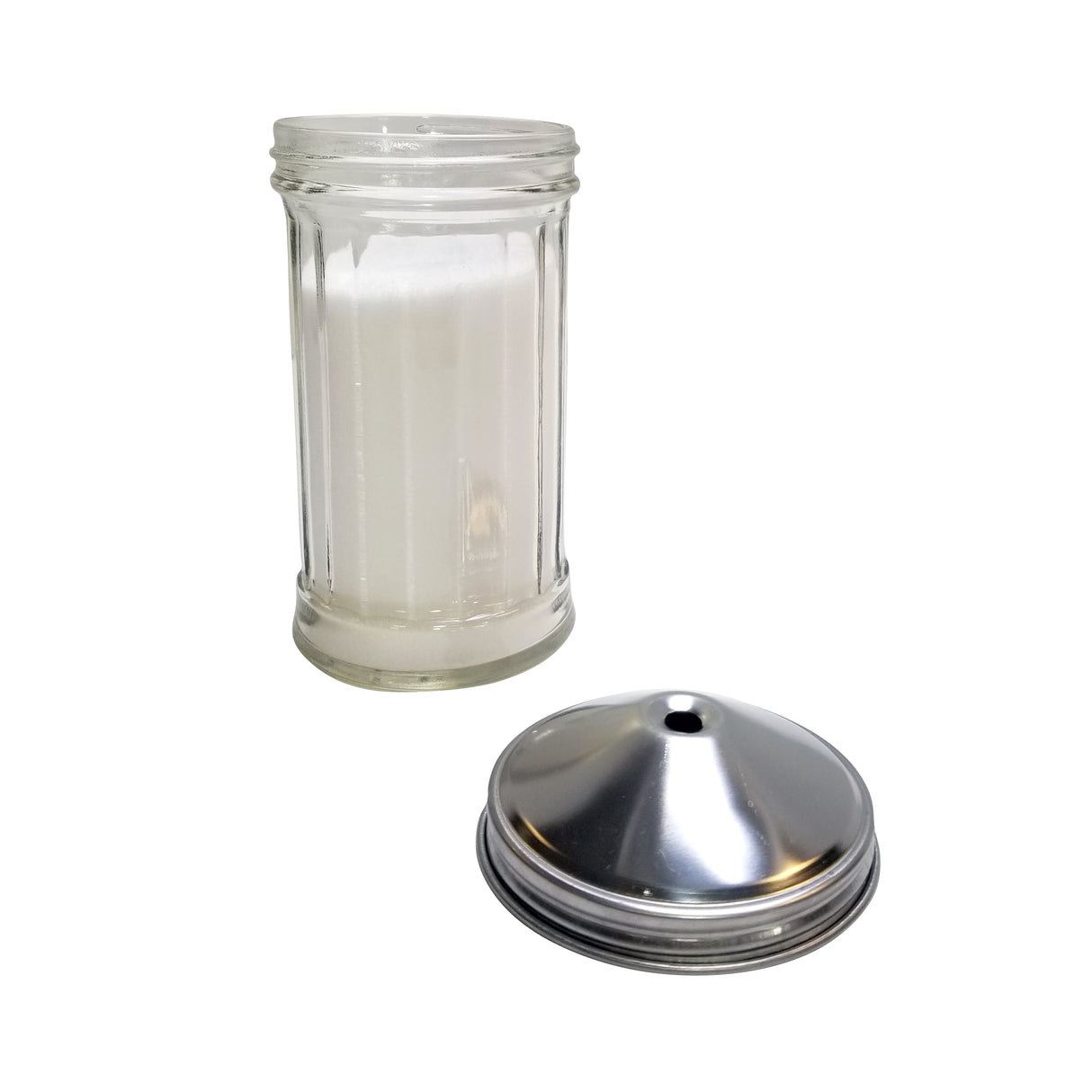 A clear, cylindrical glass salt shaker filled with salt stands upright, its stainless steel lid with a single center pour hole resting beside it on a white background. The lid is detached, exposing the shaker’s open top.