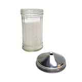 A clear, cylindrical glass salt shaker filled with salt stands upright, its stainless steel lid with a single center pour hole resting beside it on a white background. The lid is detached, exposing the shaker’s open top.