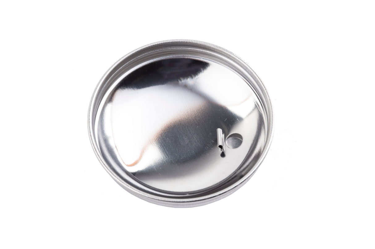 A shiny, round sugar pourer top is shown on a white background. The stainless steel lid has a small circular hole and a narrow slit near the edge, but no pull tab. Its metallic surface reflects light and appears smooth.