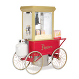 A vintage-style red outdoor popcorn maker cart with gold accents, large spoked wheels, a propane tank, and a glass LP gas popcorn popper filled with corn. Two striped popcorn boxes sit on the side shelf. Popcorn is written on the cart and glass.