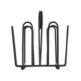 A black powder coated metal napkin holder with a geometric, open-frame design; it features upright, U-shaped wire loops forming a symmetrical structure—perfect as a Jelly Packet Rack. The holder sits on small rounded feet.