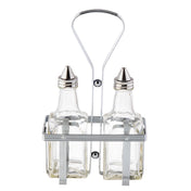 Two clear glass bottles with stainless steel tops are held upright in a rectangular metal caddy. The Oil & Vinegar Dispenser set features vertical bars and a tall looped handle for easy carrying, with both bottles empty and positioned side by side.