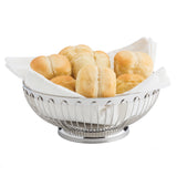 A stainless steel TableCraft Regent Basket lined with a white napkin holds six golden-brown bread rolls. The rolls are neatly arranged inside the basket, set against a plain white background.