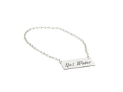 A silver chain with a rectangular metal tag attached. The tag, an Urn Sign by Cal-Mil, is engraved with the words Hot Water in a decorative script font. The background is plain white.