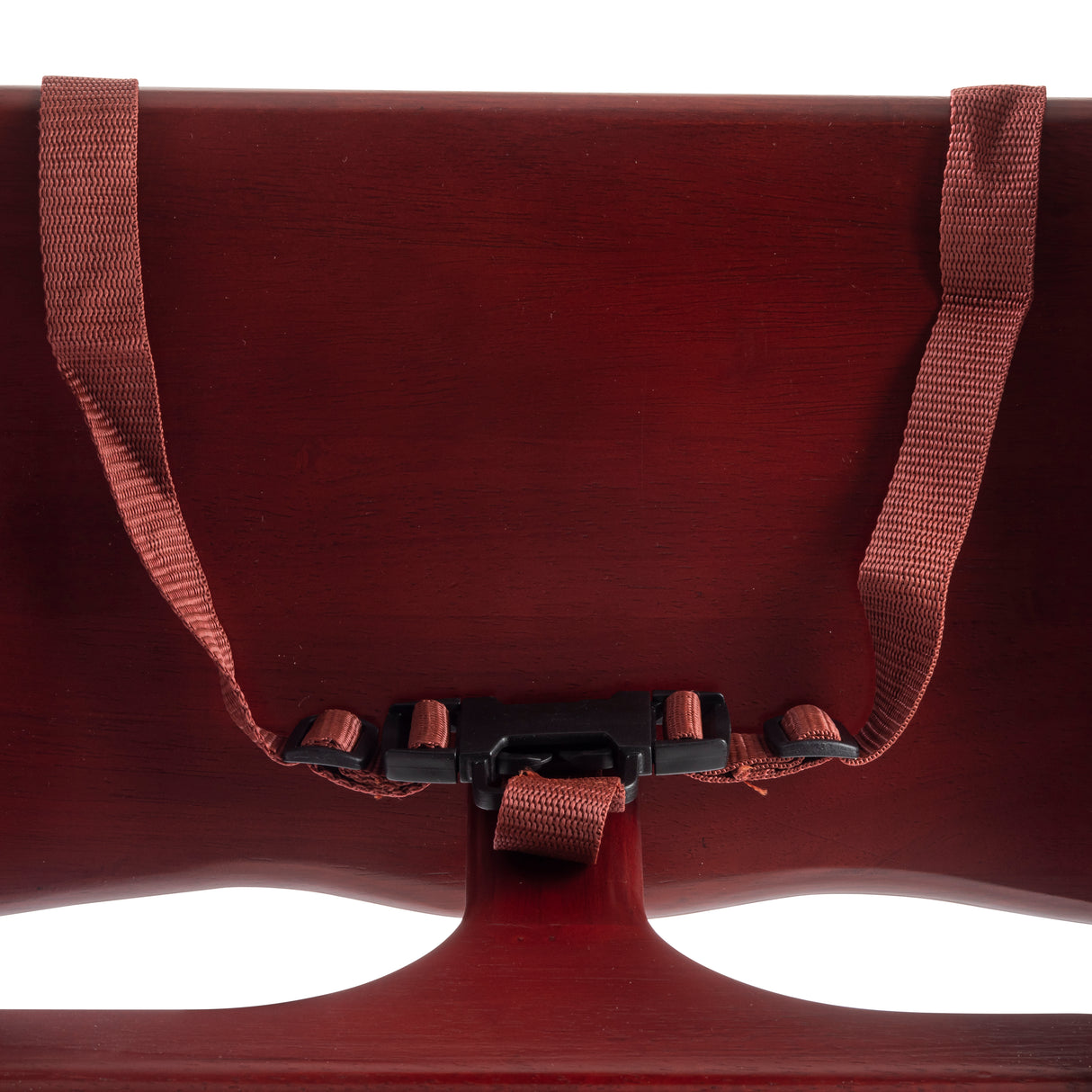 Close-up of a dark red rubberwood chair back with a reddish-brown adjustable fabric strap and black plastic buckle fastened across the center. The focus is on the backrest and attached strap, highlighting texture and curved shapes.
