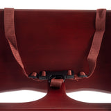 Close-up of a dark red rubberwood chair back with a reddish-brown adjustable fabric strap and black plastic buckle fastened across the center. The focus is on the backrest and attached strap, highlighting texture and curved shapes.