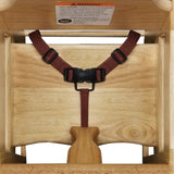 A top-down view of a stackable wooden high chair with a dark red safety harness and plastic buckle. A wooden crotch post separates the leg openings. Features a white warning label and natural wood finish; ASTM F404-18 compliant.