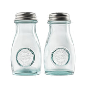 Two empty, clear recycled glass jars with stainless steel tops are side by side. Each shaker has a round embossed logo on the front reading Authentic Recycled Glass. The background is plain white, and the shakers are clean and unused.