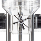 Close-up of a transparent polycarbonate cereal dispenser with a shiny, metallic, six-blade propeller inside, supported by polished vertical metal rods. The geometric shapes and reflections emphasize its industrial and modern design.
