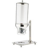 A tall, cylindrical polycarbonate cereal dispenser with a metal lid and base, featuring a lever mechanism for dispensing dry food. It is mounted on a shiny, rectangular metal stand with four rounded feet and a circular cutout to hold bowls or cups.