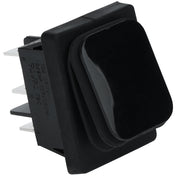 A close-up of a black rectangular rock switch with a slightly raised, rounded top and multiple metal prongs for electrical connections on the side. The switch is made of plastic and is designed for panel mounting in Empura Equipment.
