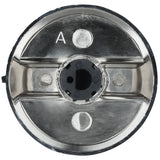 Close-up of an Empura oven knob, a metallic, circular object with a shiny surface and indented center featuring a black plastic core. The letter A is engraved on the top left, with three round, silver indents spaced around the center.