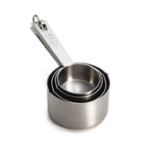 A set of four shiny stainless steel measuring cups with a metal ring holding them together. Dishwasher safe, smooth, and arranged from smallest to largest, the top cup is labeled 1/4 cup 60 ml and placed on a white background.