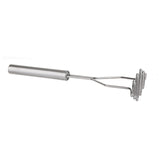 A TableCraft potato masher with a stainless steel handle and a wavy mashing plate is photographed on a plain white background, positioned diagonally with the handle on the left and mashing end on the right.