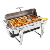A stainless steel chafing dish with a raised lid holds mixed vegetables—carrots, corn, green beans, and peas. A perforated serving spoon with a yellow handle rests inside the tray. The dish is set on a white background.