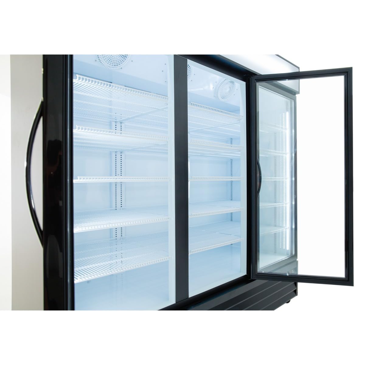 A large glass door cooler with black handles is shown. One door is open, revealing empty, clean white wire shelves inside. The brightly lit interior highlights the spotless look of this commercial refrigeration unit.