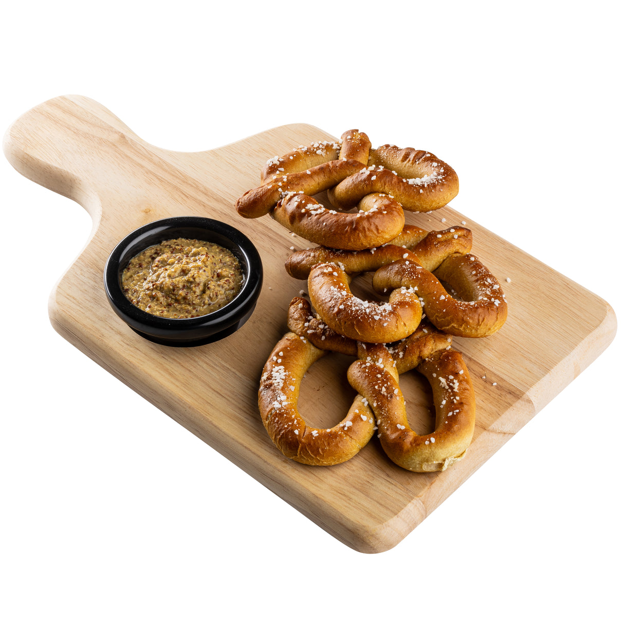 A TableCraft bread board with a natural finish wood holds several salted soft pretzels piled high, paired with a small black cup of grainy mustard for dipping. The background is plain white.