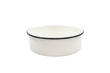A plain, round, white ceramic bowl with a smooth surface and a thin black rim around the top edge sits on a white background. Reminiscent of classic enamelware serving tray designs, the bowl features a simple, minimalist style.