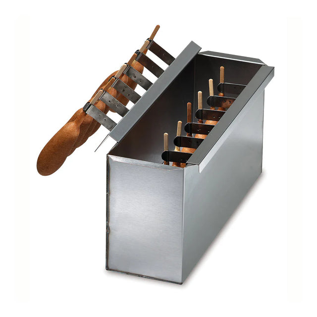 A rectangular stainless steel batter dip tank for making treats like corn dogs or ice cream bars, with a hinged lid partially open, showing wooden sticks in the dark liquid. A wooden-handled tool with metal tines rests on top. Background is plain white.