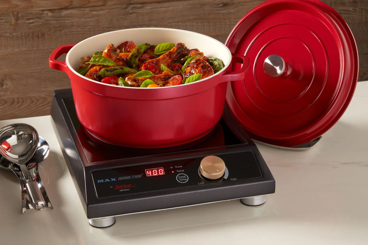 A red Ironlite Casserole filled with cooked food sits on a black induction cooktop with digital controls, displaying 488 in red numbers. The casserole lid rests nearby on the white countertop, and a metal kitchen utensil is visible to the left.