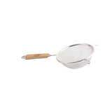 A metal strainer with a medium mesh sieve and round rim is shown. It features a sturdy wooden handle on one side and a small metal hook for resting on a bowl or pot. The background is plain white.
