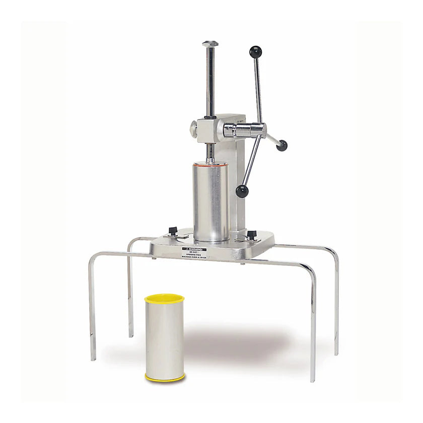 A manual Churro Extruder with a vertical stainless steel cylinder sits on a metal frame with four legs. Two black-handled levers are attached to the top. A cylindrical container with a yellow rim is placed in front for making 1" churros.