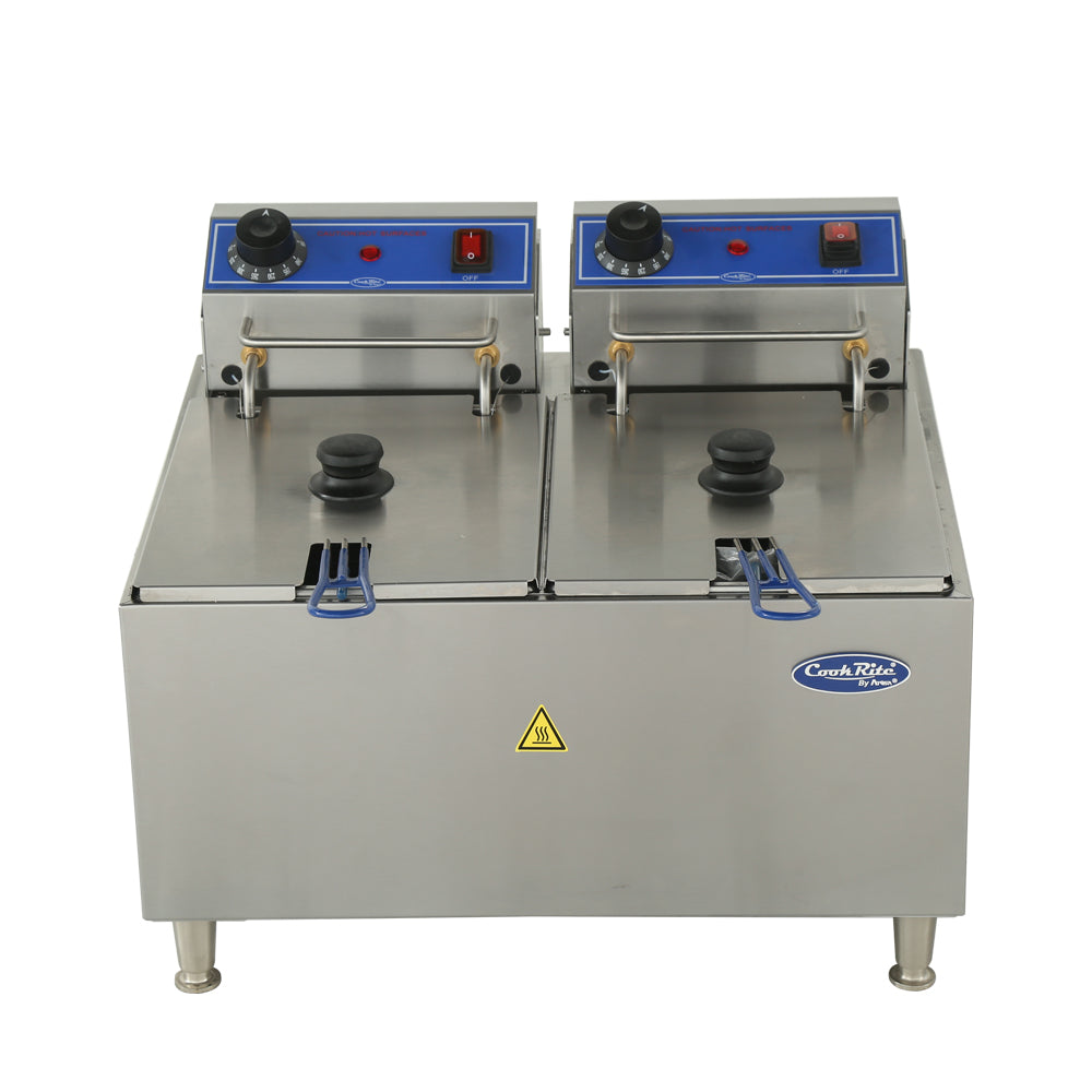 A stainless steel electric countertop fryer with a 32 lb. fat capacity features two lidded compartments, each with black handles, control knobs, temperature dials, and red indicator lights on top, plus a yellow caution sticker and “Cook Rite” logo on the front.