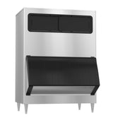 A commercial ice storage bin made of stainless steel, featuring four metal legs, a large black front access door, and a rectangular black panel on the upper front section, set against a plain white background.