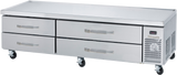 A stainless steel refrigerated chef base with four horizontal drawers and a right-side ventilation panel sits on caster wheels. The flat surface is ideal for prepping food, making it a versatile equipment stand in restaurant kitchens.