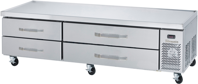 A stainless steel refrigerated chef base with four horizontal drawers and a right-side ventilation panel sits on caster wheels. The flat surface is ideal for prepping food, making it a versatile equipment stand in restaurant kitchens.