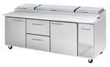 A large commercial stainless steel refrigerated prep table with three covered compartments on top, two drawers, and two doors below. This three-section Pizza Prep Table by True features vents for cooling and four caster wheels, set against a plain white background.