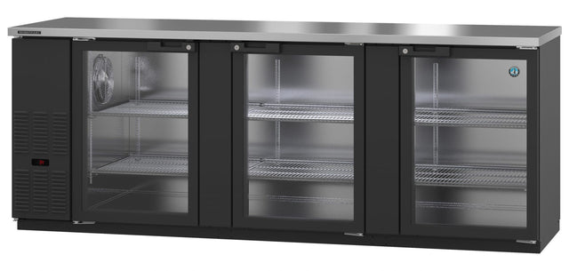 Three-section commercial bar refrigerator with a stainless steel top, three transparent doors, and multiple wire shelves inside each section. The left section features ventilation grills and a digital temperature display. This glass door cooler is clean and empty.