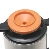 A close-up of a glass vacuum insulated metal thermos with a black handle and an orange plastic lid featuring a central hole and the words CLOSE TIGHTLY embossed along the rim. The Thermal Server lid also has arrows indicating the direction to close.