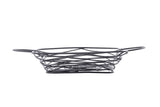 A black powder coated metal Artisan Collection Basket with an open, crisscross pattern and two side handles. The empty, oval-shaped basket features integrated ramekin holders and sits on a plain white background.